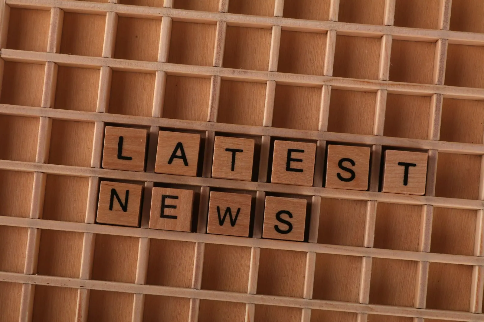 Wooden letter blocks spelling Latest News on a grid background, ideal for media themes.