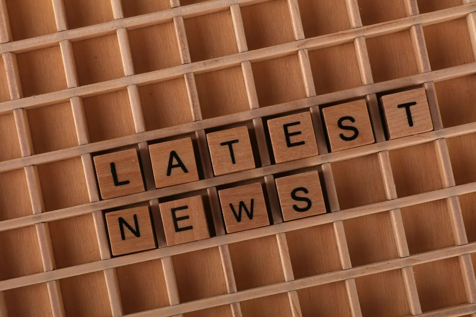 Wooden letter blocks spelling 'Latest News' on a grid surface. Ideal for media concepts. Desk case: explaining a jobs report on release day