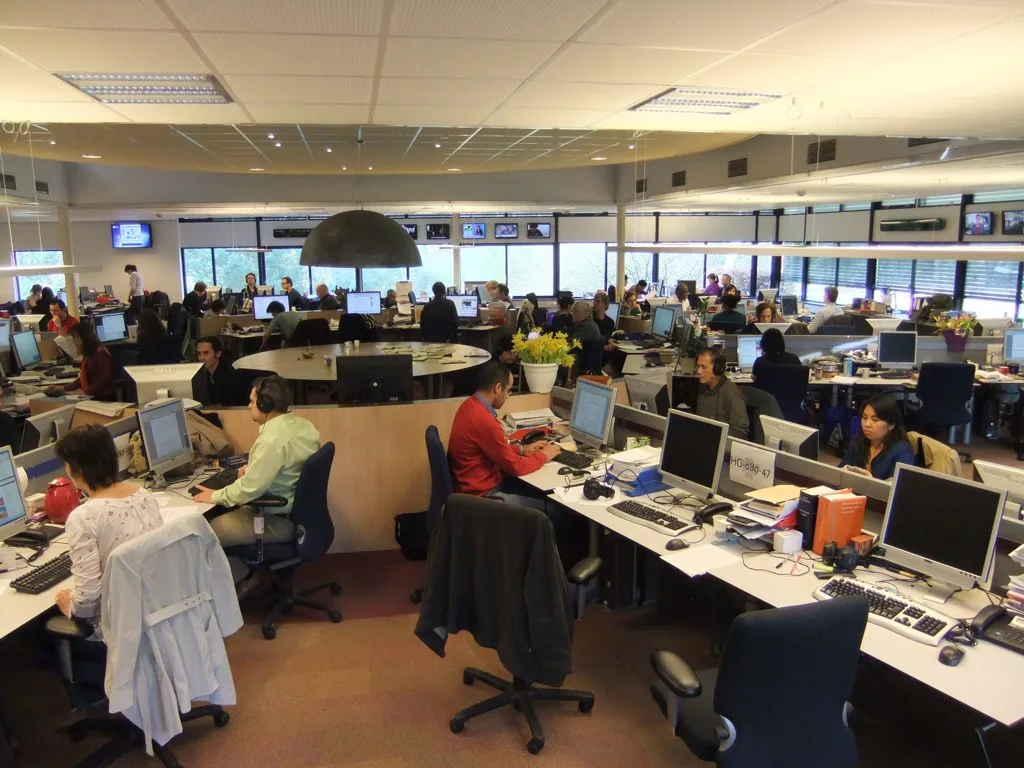 Journalists and editors working around a central newsroom desk